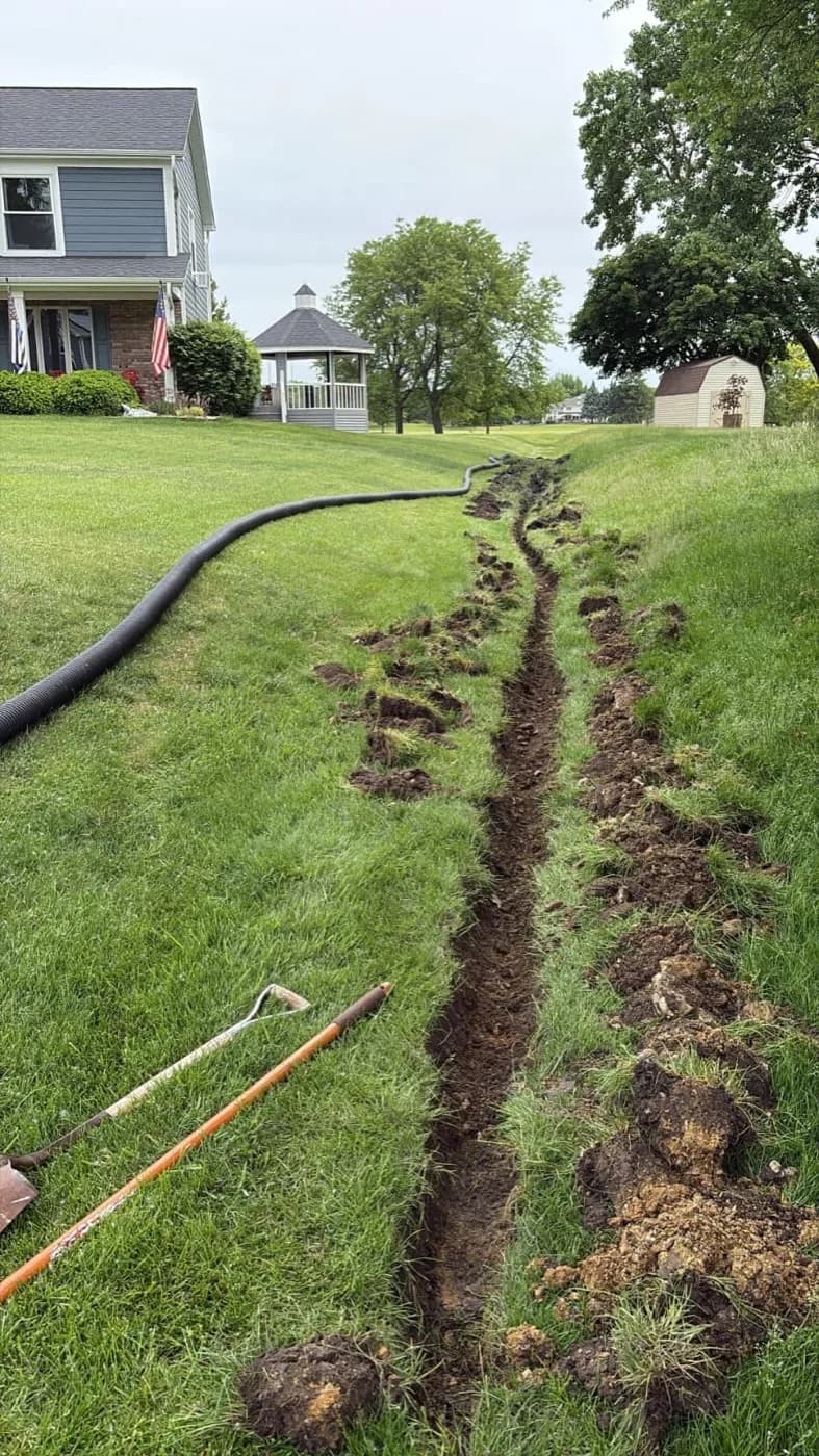 Drain trench cut across a large lawn to carry water away from the house