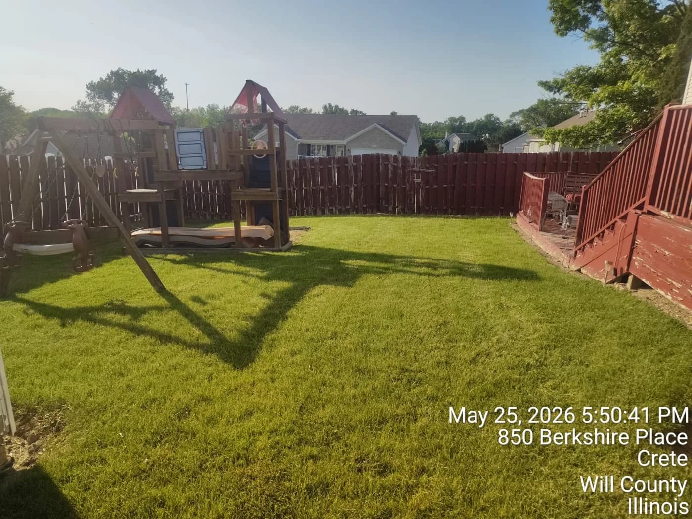 Fenced backyard cut clean around a wooden playset