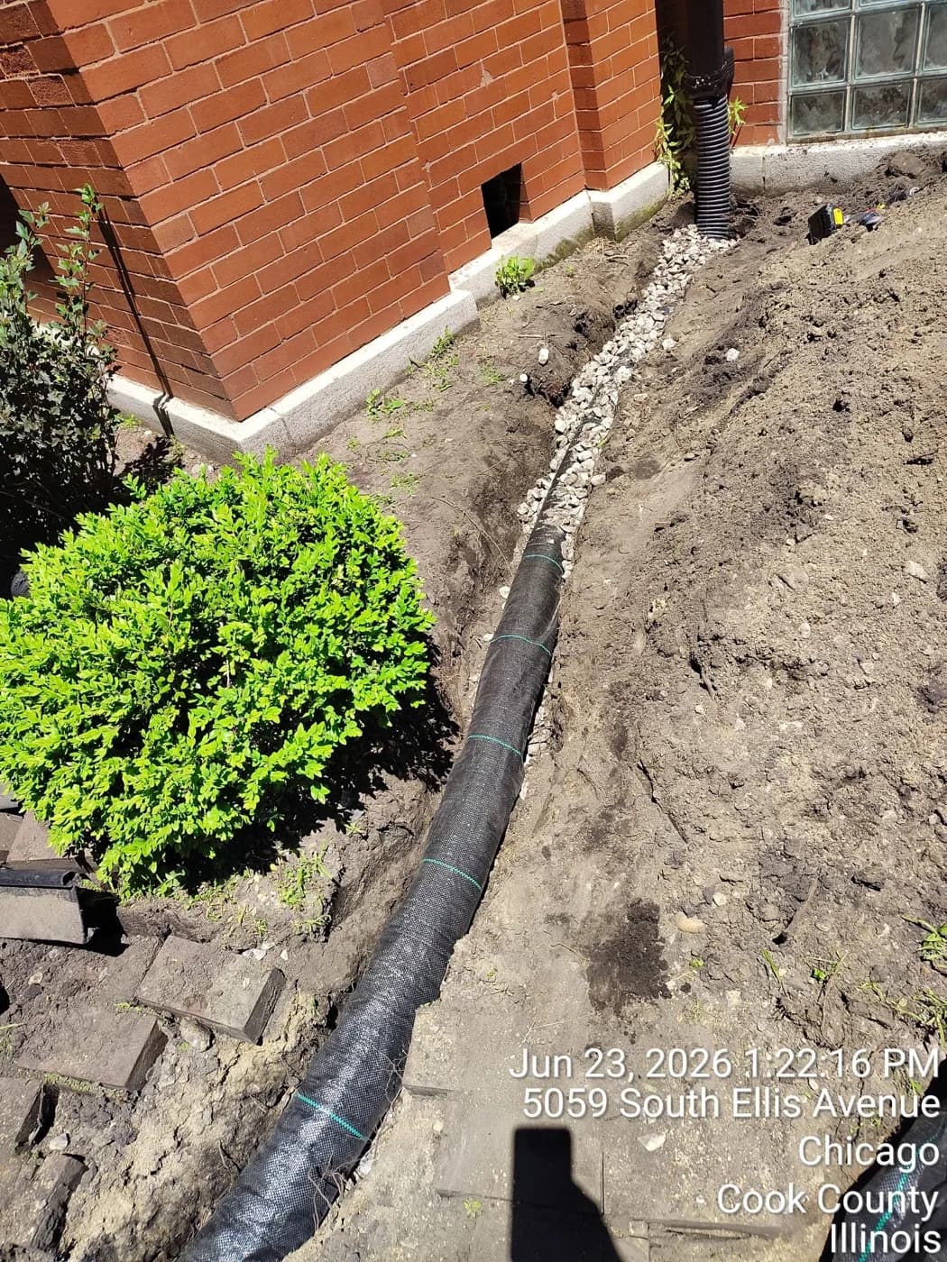 Solid drain line trenched along a brick foundation and backfilled with gravel