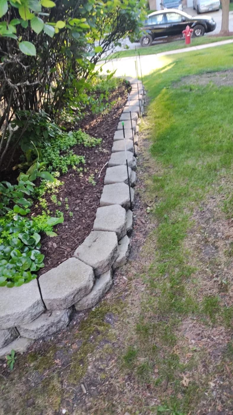 Stacked stone edging curving around a bed at the lawn line