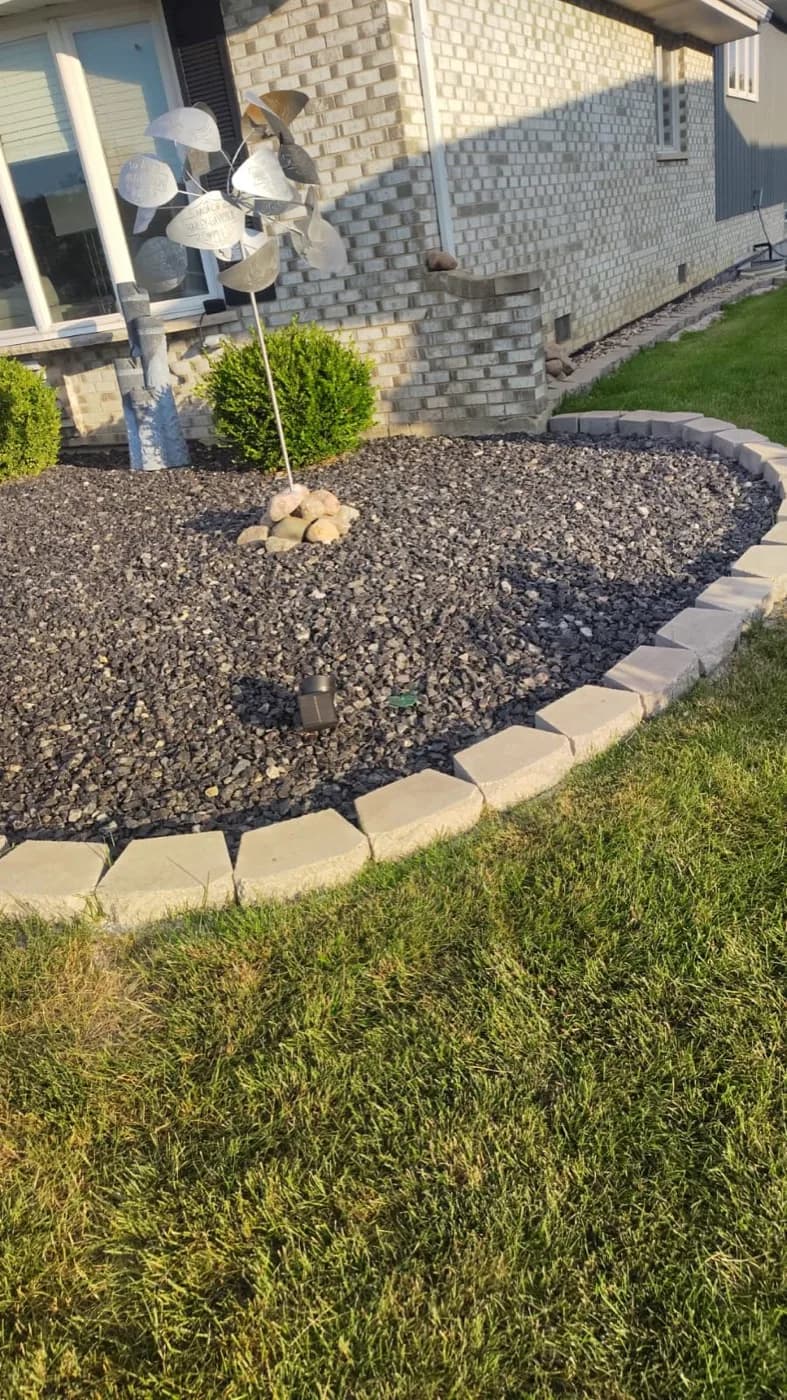Decorative stone bed held by a tan paver border